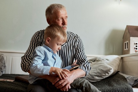 Grandfather and grandson using digital tablet while sitting on couchの写真素材