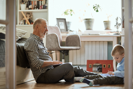 Grandpa looks photo album with his wedding, little boy using electronic tabletの写真素材