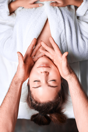Woman enjoying anti aging facial massage. Upside down photo of relaxing womanの写真素材