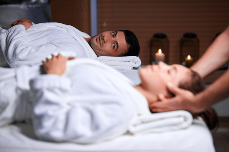 Beautiful young woman receiving massage on head and shoulders zone in spa centreの写真素材