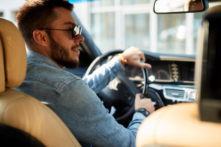 young unshaven man looking at the right side pf the road while driving