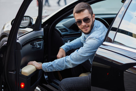 handsome gorgeous man is opening the door of his new car