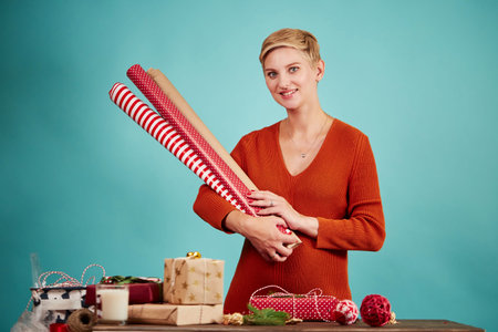 Young blonde woman holding in hands wrapping paper rolls for gifts, isolated.