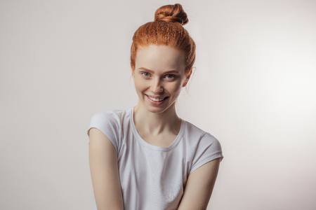 Redhead girl with hair bun and freckles isolated over grey backgroundの写真素材