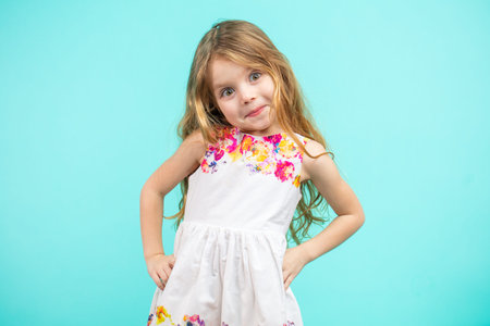 Cute small girl wearing a flowers summer dress isolated on blue