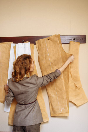 Female tailor choosing clothing paper pattern at snipper workshop