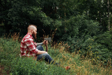 Lumberjack sitting in forest resting after hard work