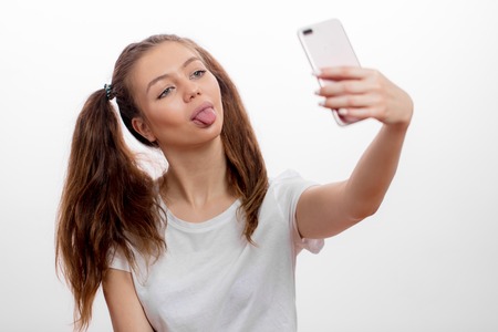 funny, awesome girl sshowing her tongue while taking selfieの写真素材