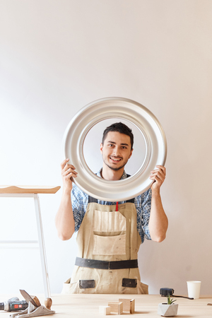 Confident young woodworker standing next to workbench in his carpentry workshopの写真素材