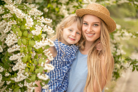 Lifestyle portrait mom and daughter in happines at outside looking at camera