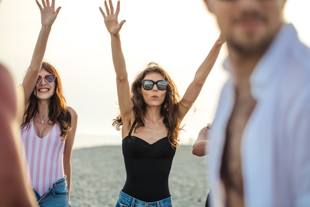 Friends dance on beach under sunset sunlight, having fun, happy, enjoyの写真素材