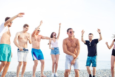 Friends dance on beach under sunset sunlight, having fun, happy, enjoyの写真素材