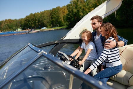 father with adorable daughter and wife resting on big boatの写真素材