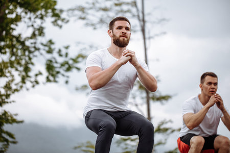 Caucasian male athletic friends doing box jump outdoor on top of the mountain.