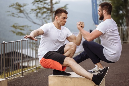 Musculat guys showing one leg squat exercise, close up, outdoor workoutの写真素材