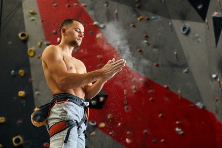Climber coating his hands in powder chalk magnesium to climb indoor, close-upの写真素材