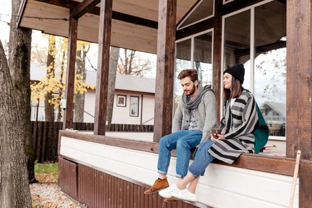 Happy young couple sitting outdoor, in front of their new home in autumn dayの写真素材