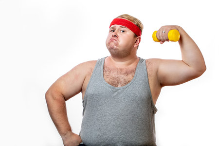 Fat funny man in red headband shows his muscles with dummbell and emotionsの写真素材