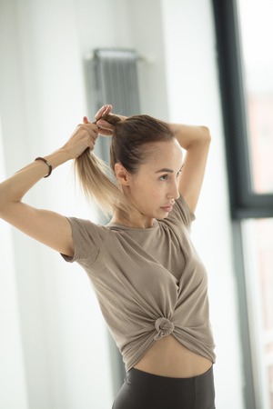 A pretty blond woman is tidying her hair while training.の写真素材