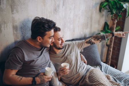 Perfect morning begins with lover and coffee in bed. Two guys resting in bed.の写真素材