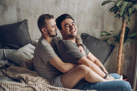 Two sexy caucasian gay guys hugging and having fun in bed indoorsの写真素材