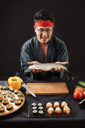 emotional surprised man holding big fish in the kitchen roomの写真素材