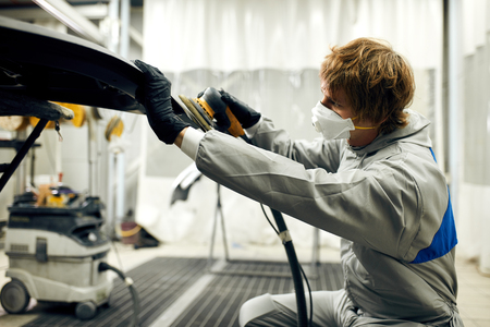 mechanic grinds car part for painting. Car body work auto repair paint after accidentの写真素材