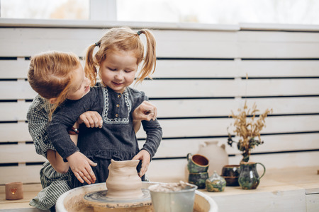 positive elder sister looking at her hardworking little sister while creating a bowlの写真素材
