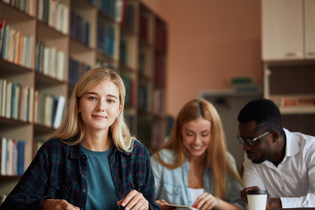 Blonde happy beautiful woman female student attends university classes indoors.の写真素材