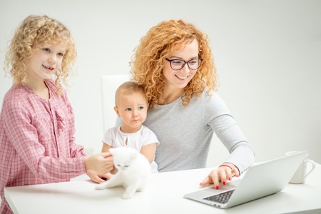awesome positive red-haired girl browsing the Net with her little childrenの写真素材