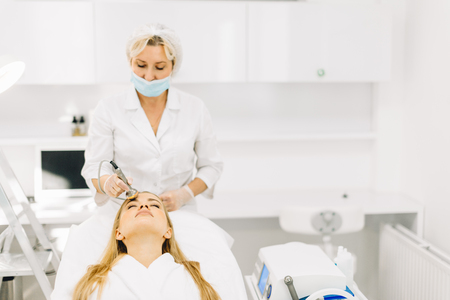 Blonde woman has ultrasonic dinamic lift massage in spa, hardware apparatus.の写真素材