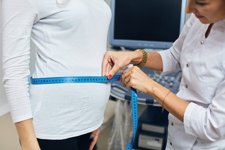nurse using the ribbon to measure the size of a bellyの写真素材