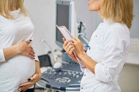 doctor writing down the complaints of a female pregnant clientの写真素材