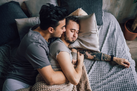 Positive delighted non-traditional couple sleeping togetherの写真素材