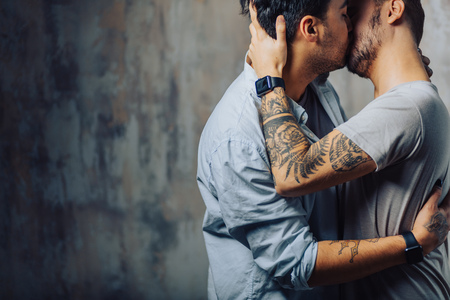 Cay couple enjoy togetherness indoors, kiss each otherの写真素材