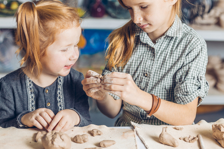 girl showing her little sister to create a clay toysの写真素材