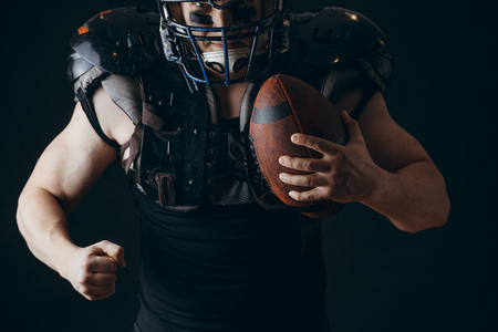 American football player with ball wearing helmet and protective shieldsの写真素材