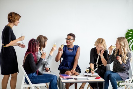 Portrait of female business team in modern studio with glasses of champagne.の写真素材