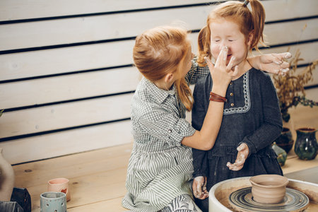 two positive girls playing with clay during the workshopの写真素材