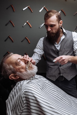 Old man getting his beard shaved by barberの写真素材