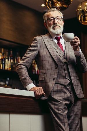 Senior businessman drinking coffee near bar counter at dark restの写真素材