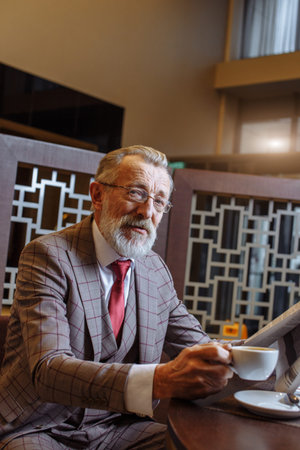 Old Businessman with laptop at coffee break in his office conceptの写真素材