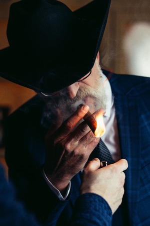 Stylish old man in wide brimmed hat and rich blue mens suit smokの写真素材