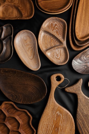 Set of cutting boards and DIY kitchen wooden utensils, plates and dishes made from oak, walnut and pine wood isolated on dark background.の写真素材