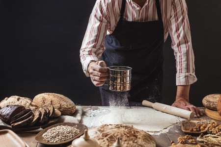 Flour being passed three times through a sieve before professional Chef put it on a piece of dough for delicate delicious pizza, close upの写真素材