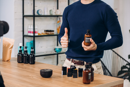 excellent elixir for keeping fit. diet, healthy lifestyle, body and face care, wellness. man is holding a bottle and showing thumb up to the cameraの写真素材