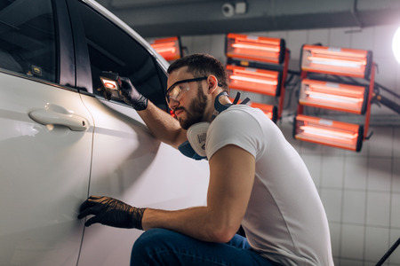 handsome bearded guy holding an equipment looking on the roof of the car. close up photo. copy spaceの写真素材