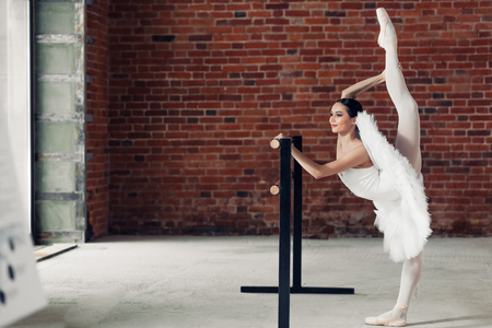 cheerful slim girl doing stretching near barre, full length photo. copy spaceの写真素材