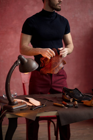 young bearded man holding leather to make shoes. close up cropped photo. job, profession