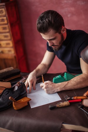 footwear designer sitting at the table and drawing model, close up photoの写真素材
